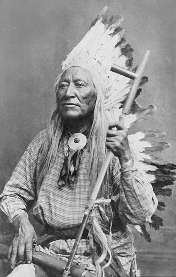 Black and white portrait of Chief Washakie wearing a feathered headdress and holding a ceremonial pipe.