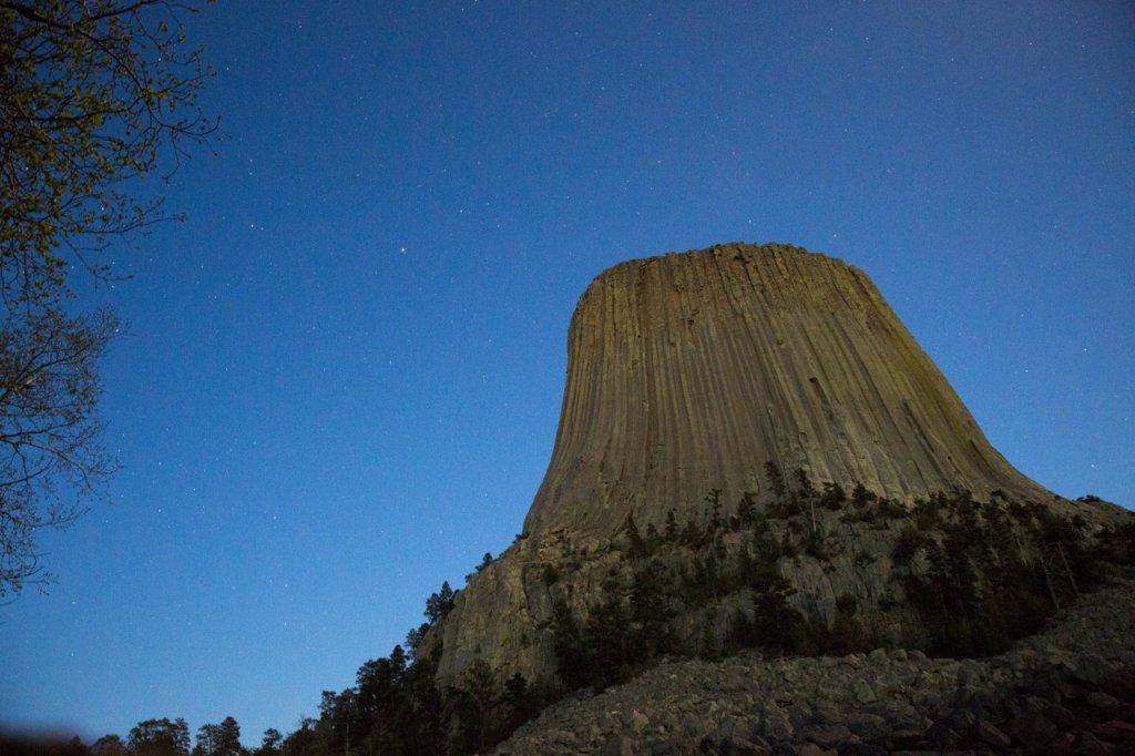8 Historic Landmarks & Sites In Wyoming 1 A close-up view of Devils Tower beneath a sky filled with stars.