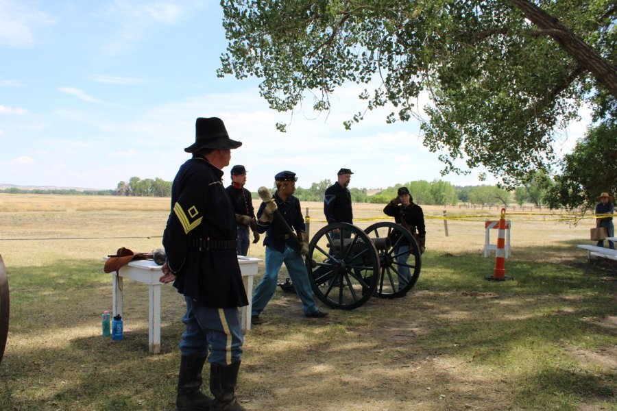 A group dressed in historic attire stands near wagon wheels at Fort Laramie National Historic Site.