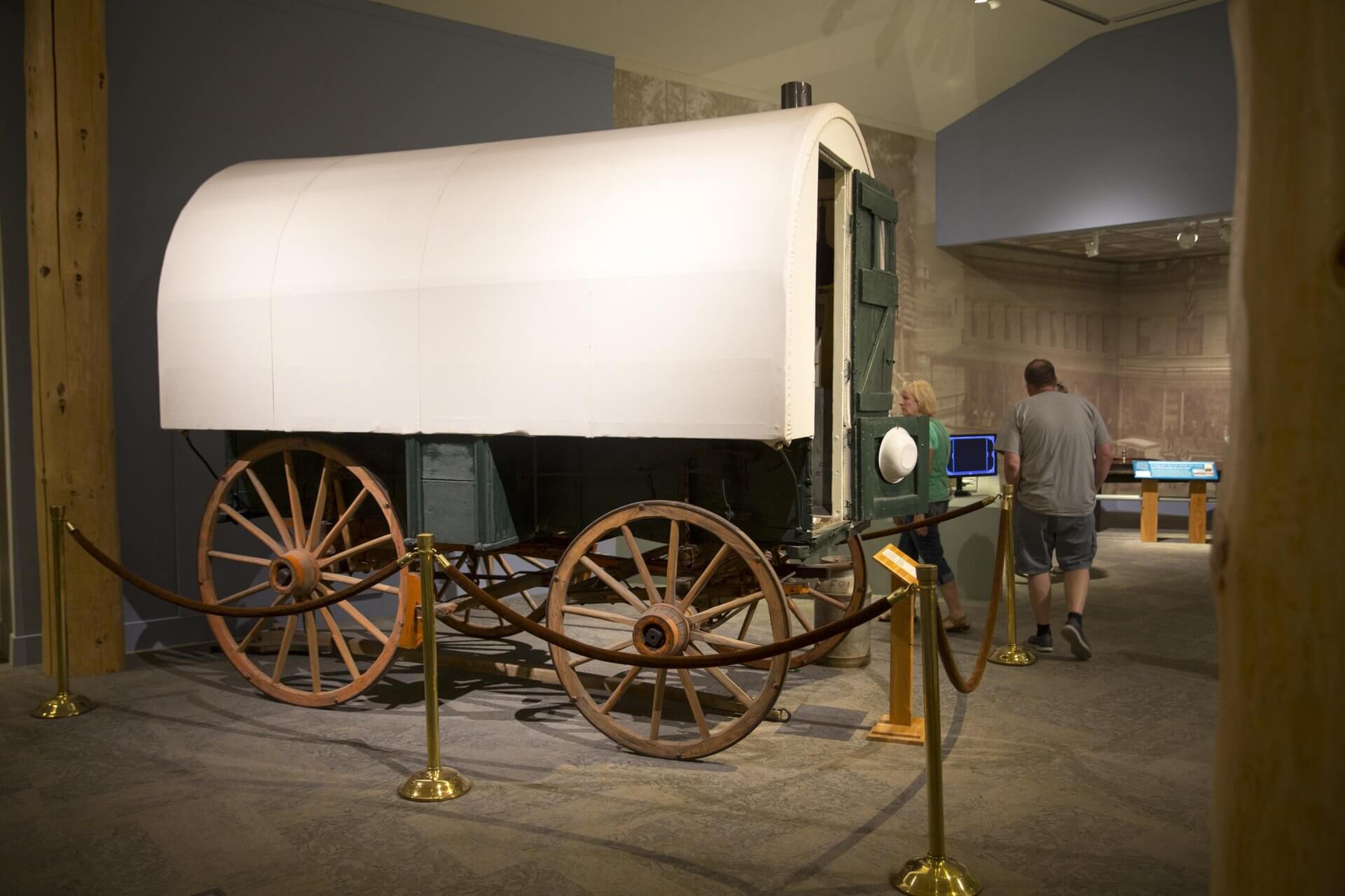 Wyoming’s Heritage: Rooted in the Modern American Spirit 3 People viewing an exhibit of a covered wagon inside the Buffalo Bill Center of the West.