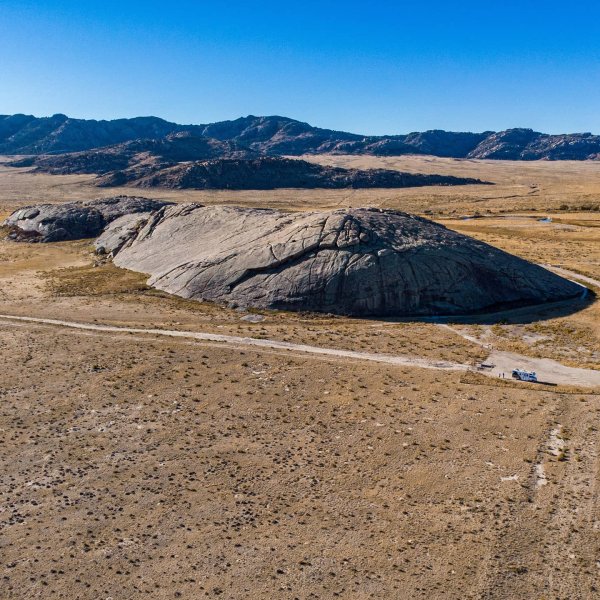 Tracing the Past: 6 Historic Trails In Wyoming 2 A distant view of rugged Independence Rock beneath a bright blue sky.