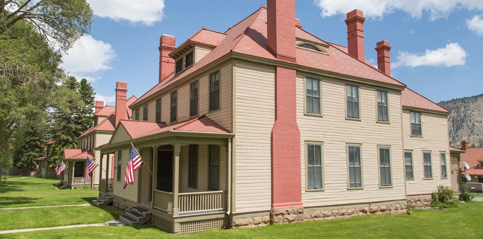 8 Historic Landmarks & Sites In Wyoming 5 Two historic buildings surrounded by grass lawns and trees at Fort Yellowstone.